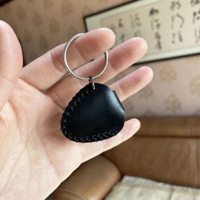 Cara trasera de un llavero de guitarra hecho de cuero auténtico con estuche para púas